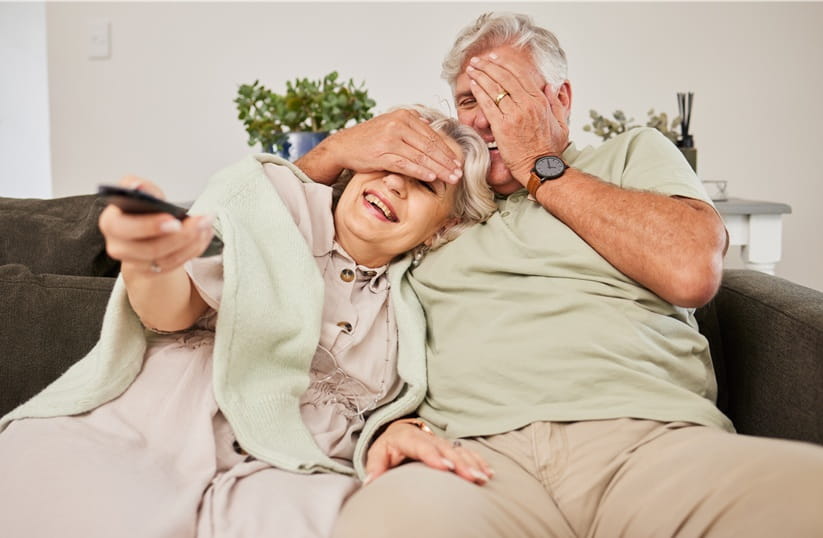 Couple laughing whilst watching TV