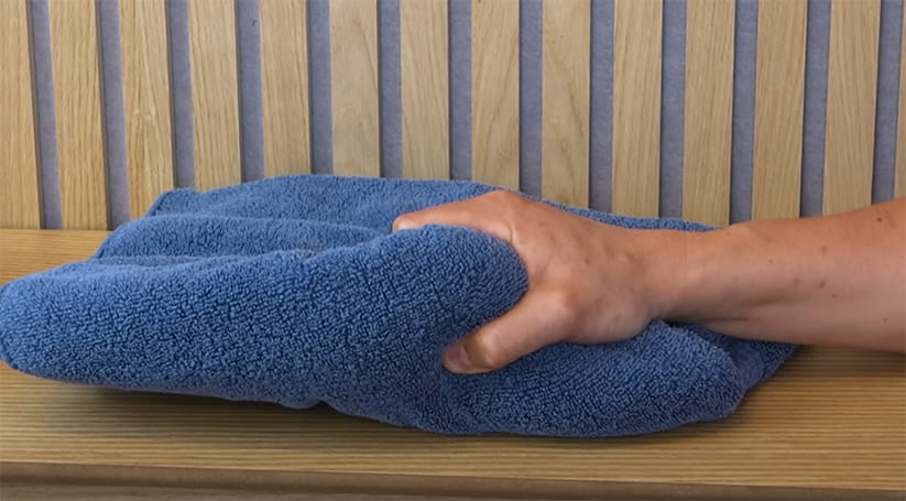 A hand gripping a blue bath towel