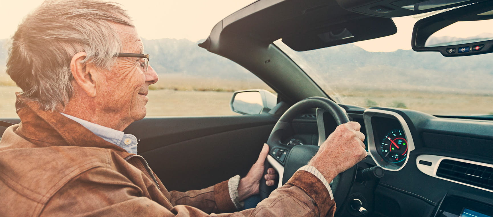 An older man driving a convertible