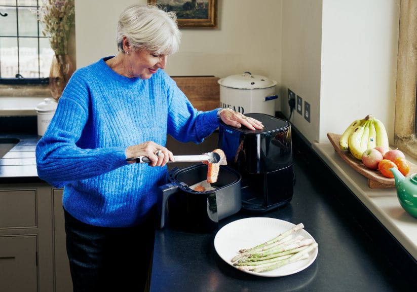 Woman serving up food from an air fryer on the counter
