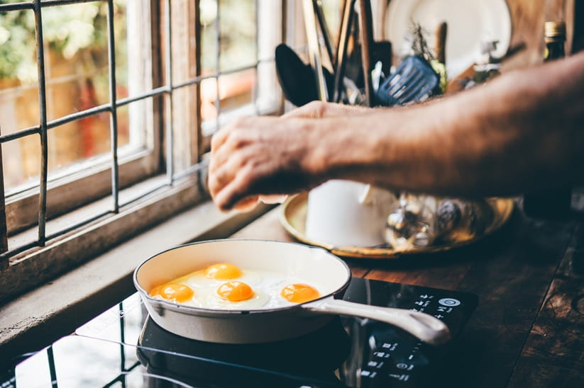 Man's hand frying eggs at home