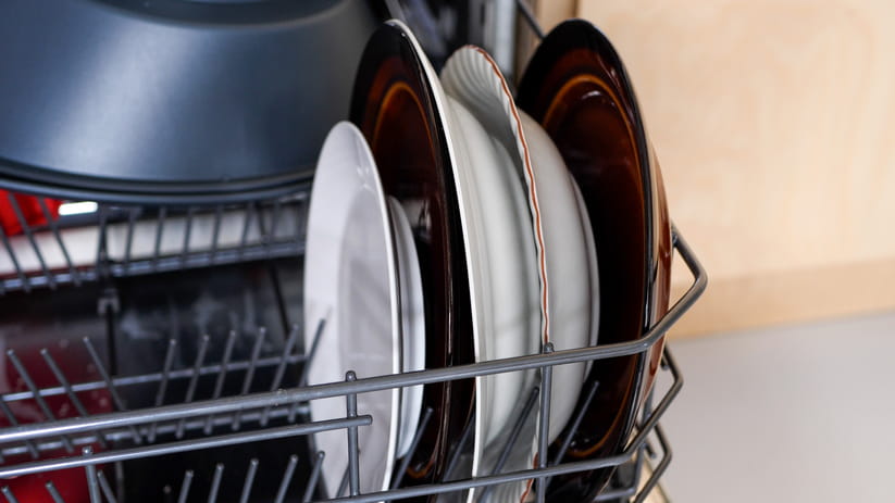 Some plates standing upright in a half loaded dishwasher