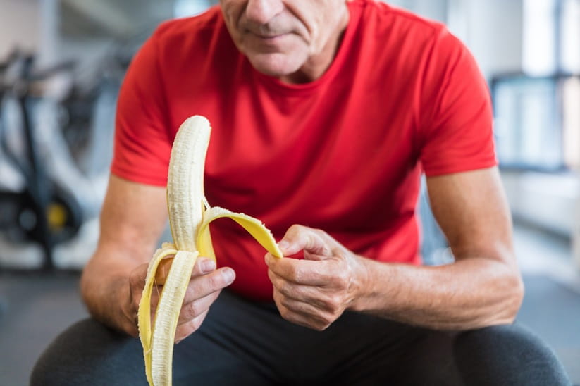 A senior man eating banana at the gym