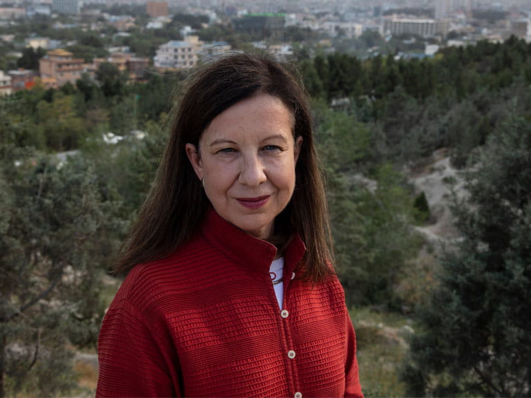 Lyse Ducet in a red jacket with a landscape and mountains in the background