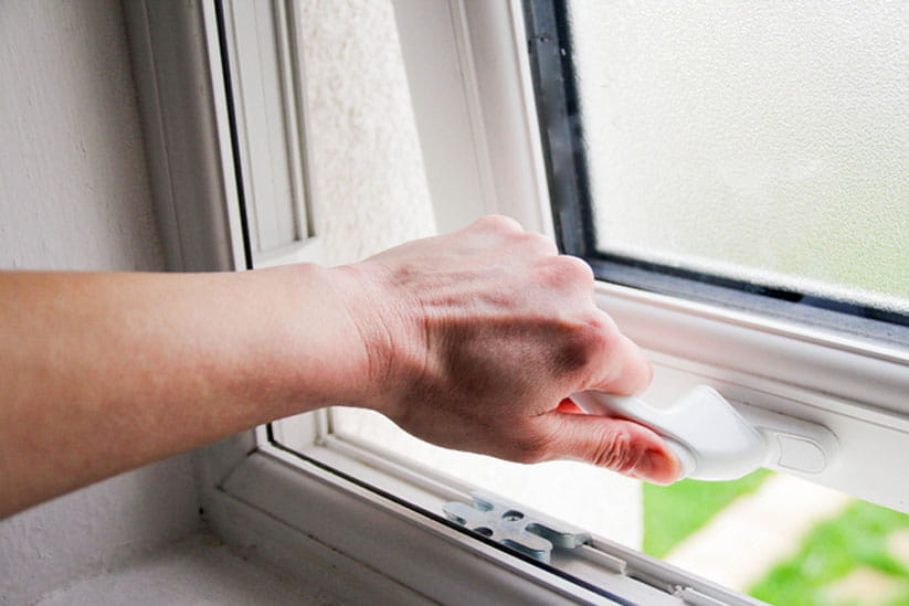 A hand closing a slightly open windor