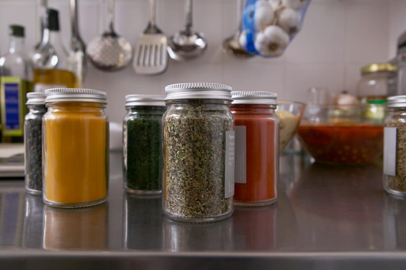 Jars of dried herbs and spices on a kitchen worktop