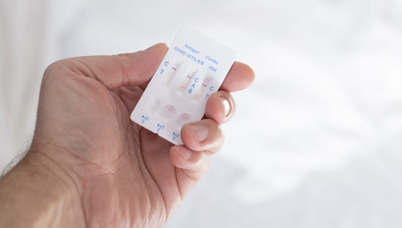 A hand holding a combination COVID-19/RSV test kit