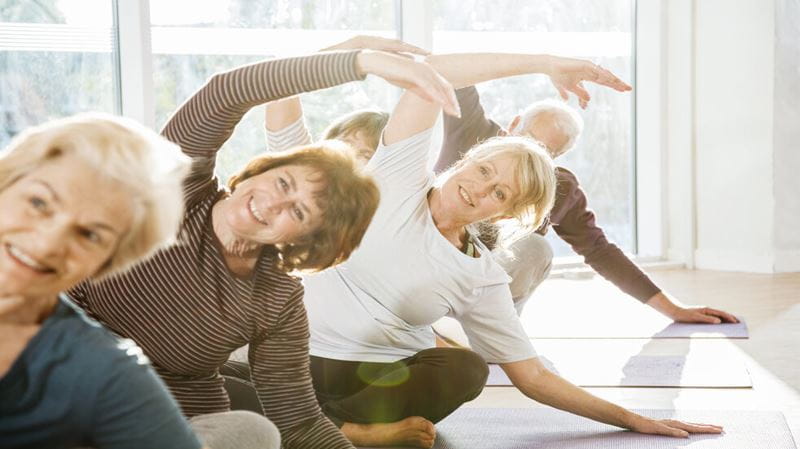 A group of women bending to one side during a yoga class