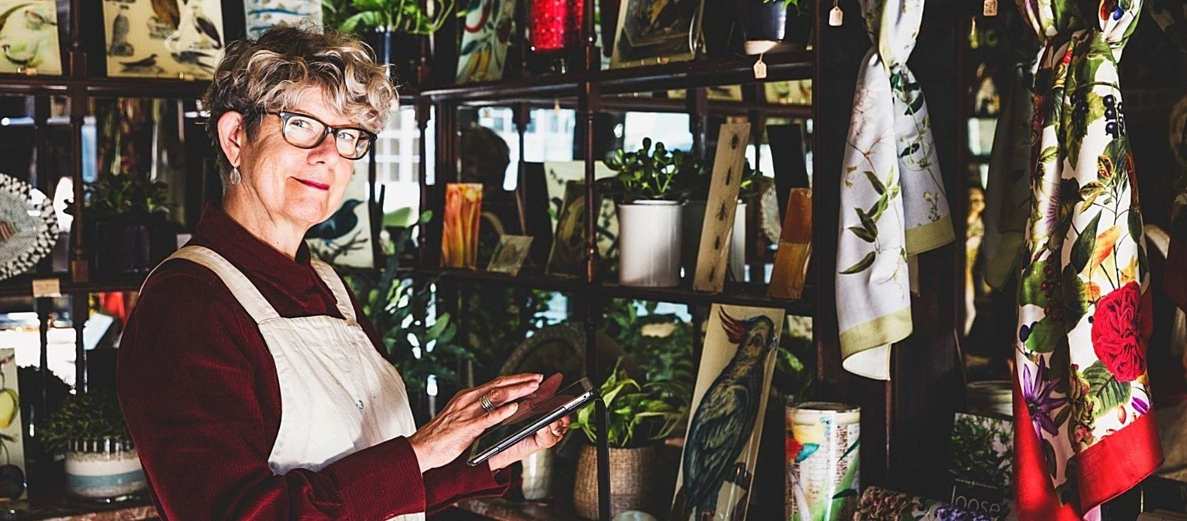 A smiling woman working in a store holding an ipad
