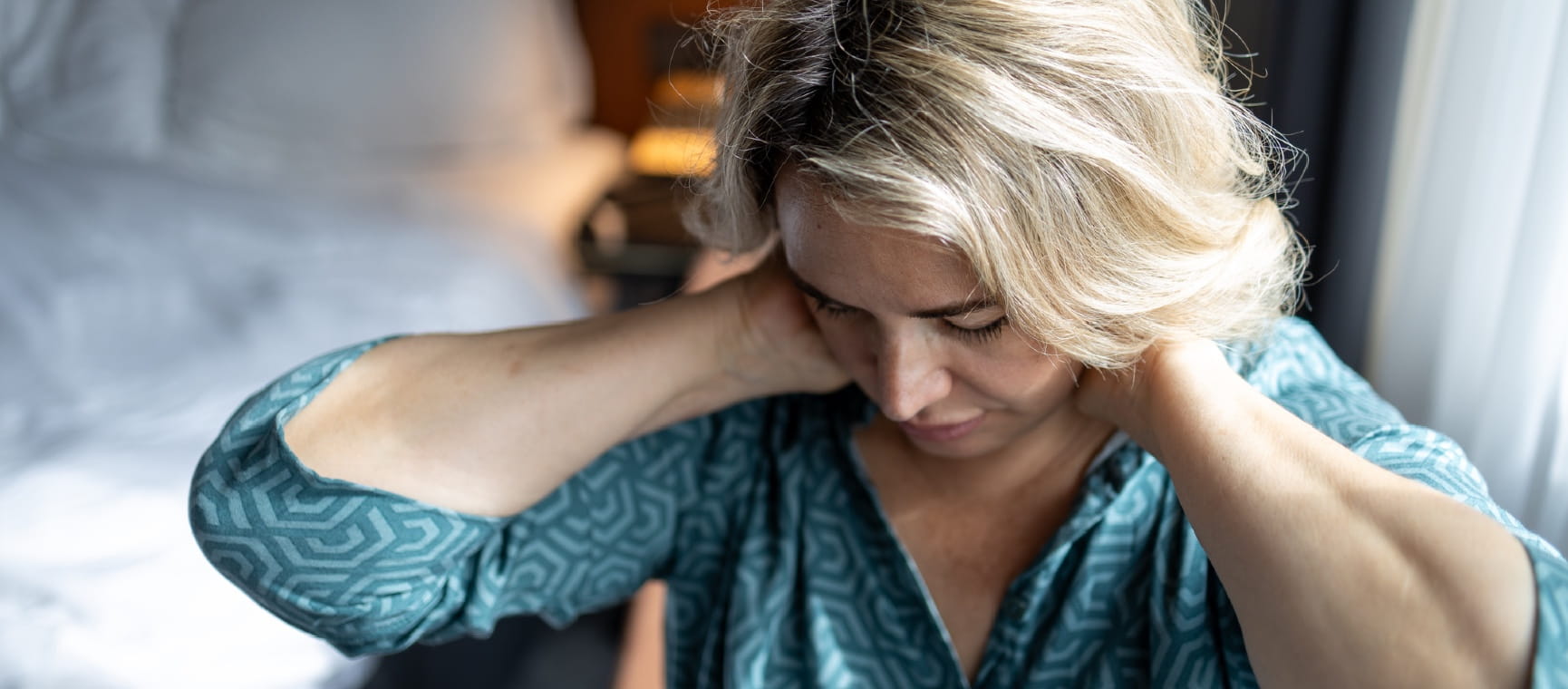 An older woman holding her hands behind her head feeling tired
