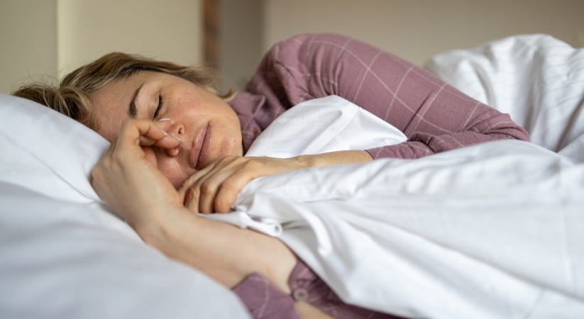 Older woman in purple pyjamas asleep in bed