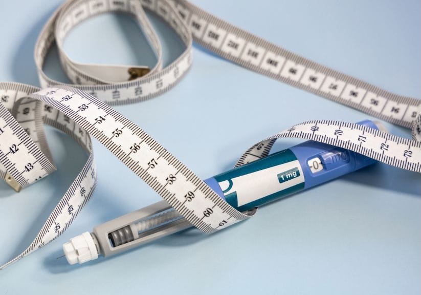 A weight loss injection with a measuring tape wrapped around it