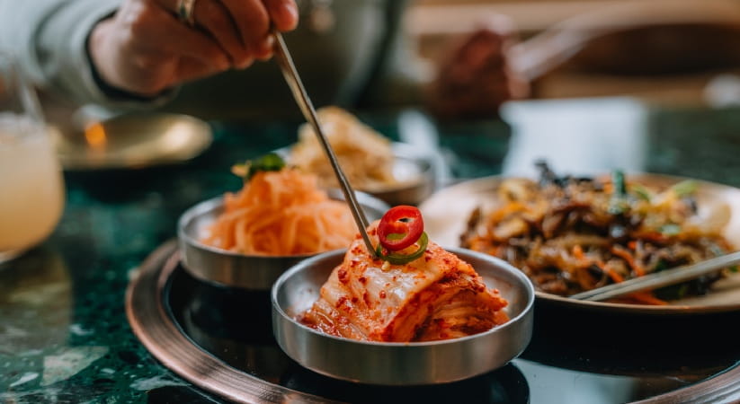Person skewering some Korean kimchi in a silver bowl