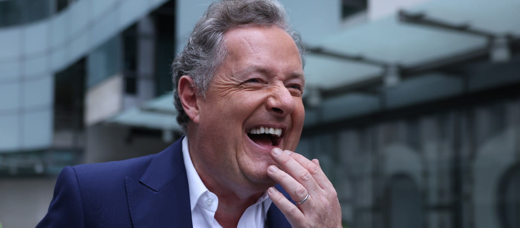 Piers Morgan laughing with his hand on his chin