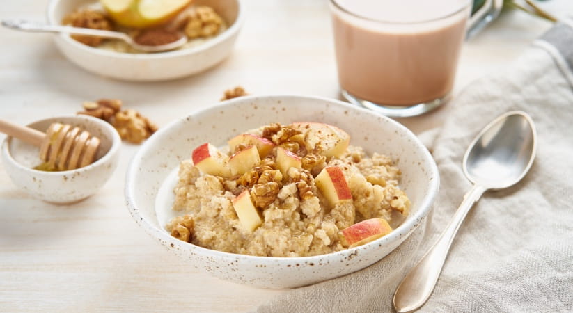 Porridge with walnuts and slices of apple on a breakfast table