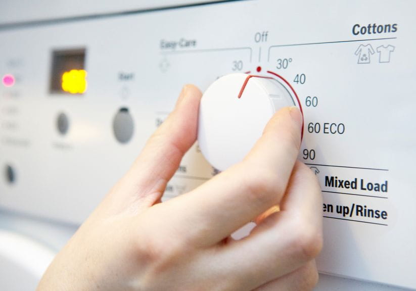Someone setting the dial on a washing machine to 30