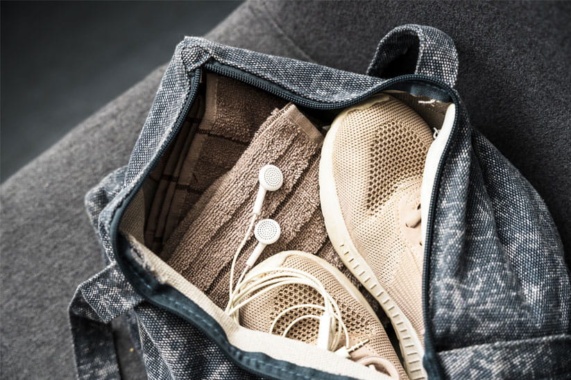 An open gym bag with shoes, a towel, and headphones
