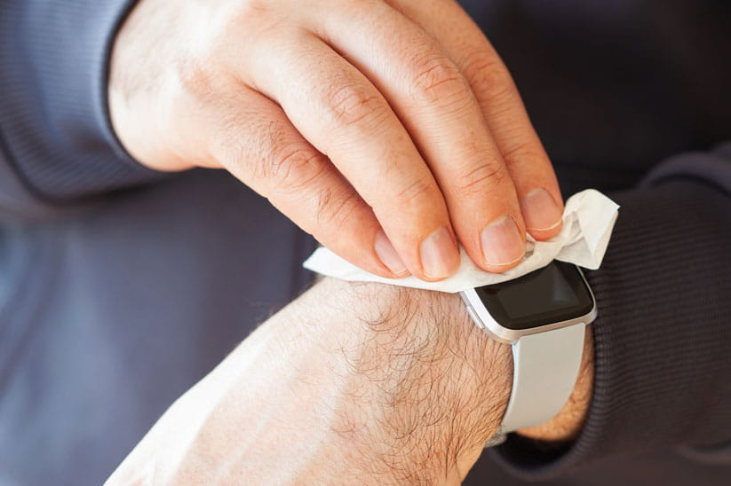 Close up of a watch strap being cleaned with a cloth while being worn on a person's wrist