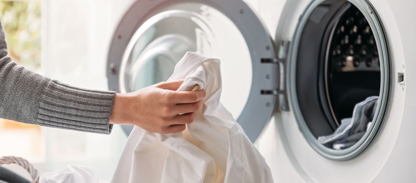 A person loading clothes into a washing machine