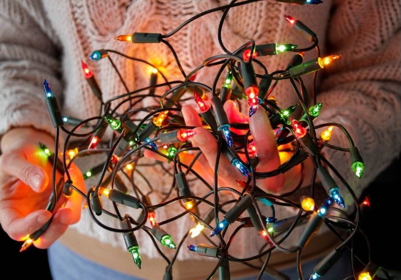 a man holding a tangle of Christmas fairy lights
