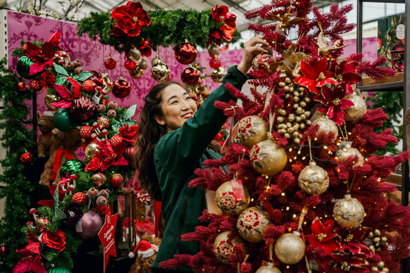 A member of Dobbies Garden Centres staff decorating a Christmas tree in-store