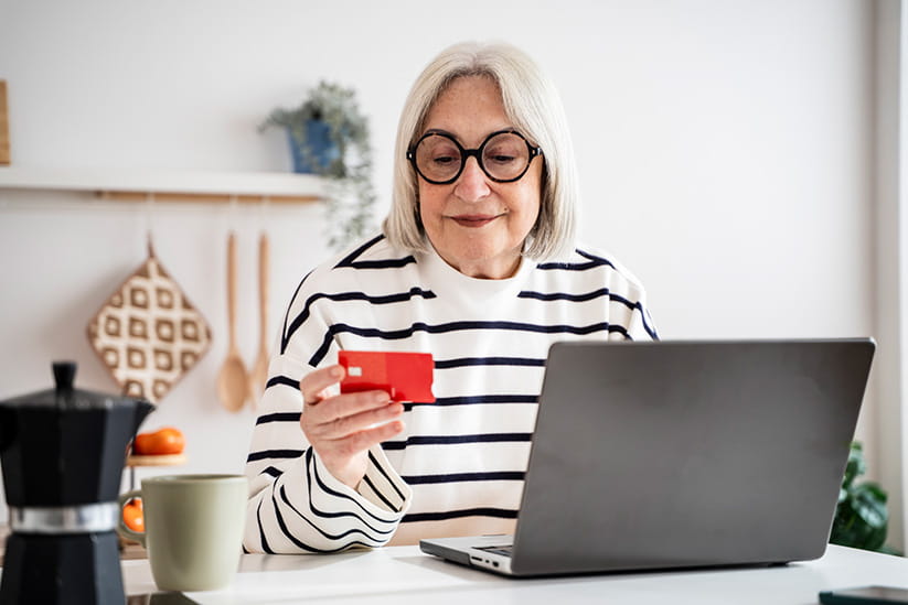 A woman checking her debit card whilst making an online purchase