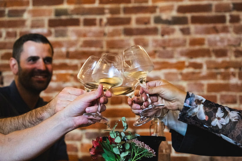 A group of people raising glasses with white wine to cheers