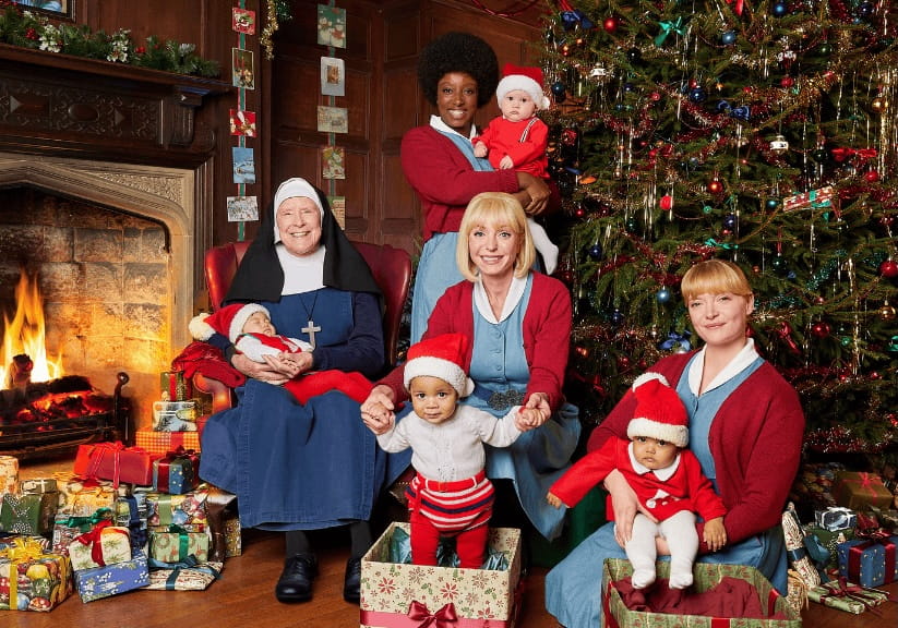 Stars of the BBC series Call the Midwife next to a Christmas tree