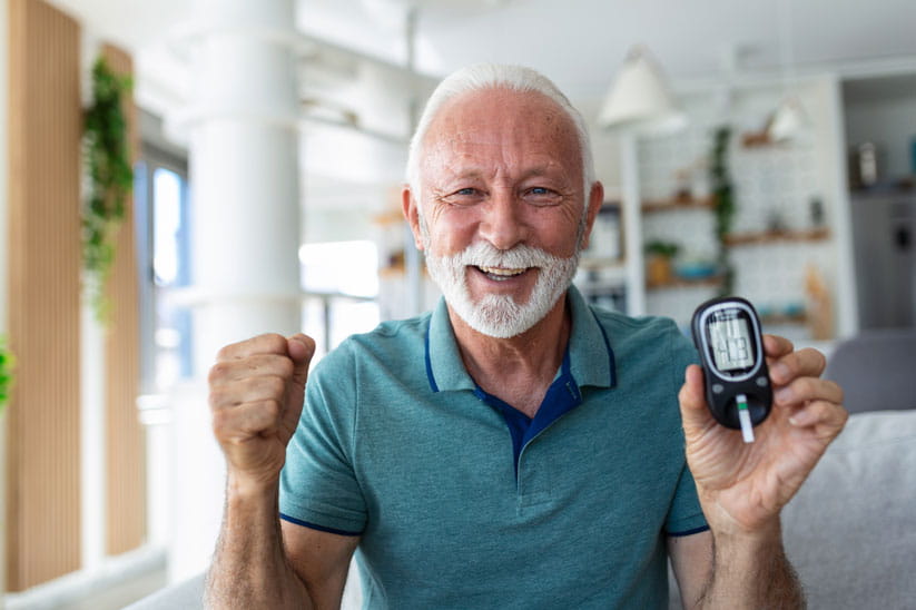 Senior man checking blood sugar level by glucometer and test stripe at home