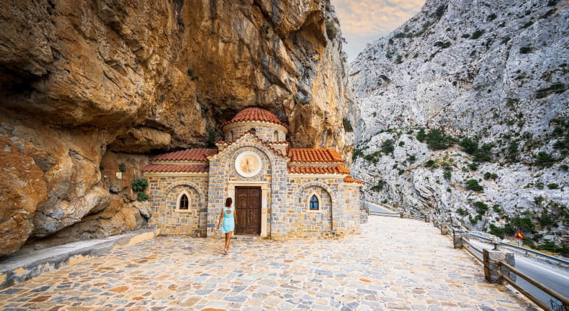 A woman looks at a small church on the beach at Kotsifou on Crete