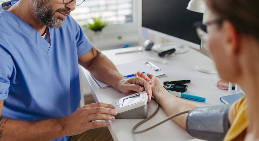 Close up of doctor in blue gown giving a man a blood test