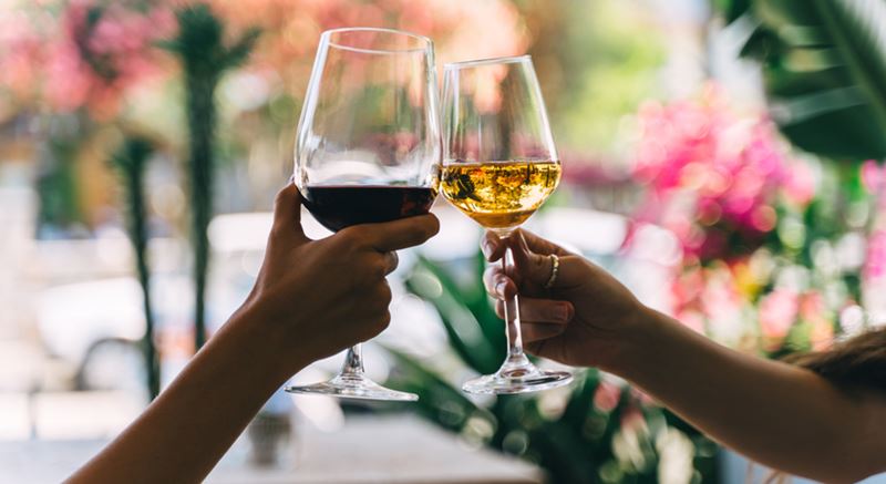 Close-up of two people clinking wine glasses