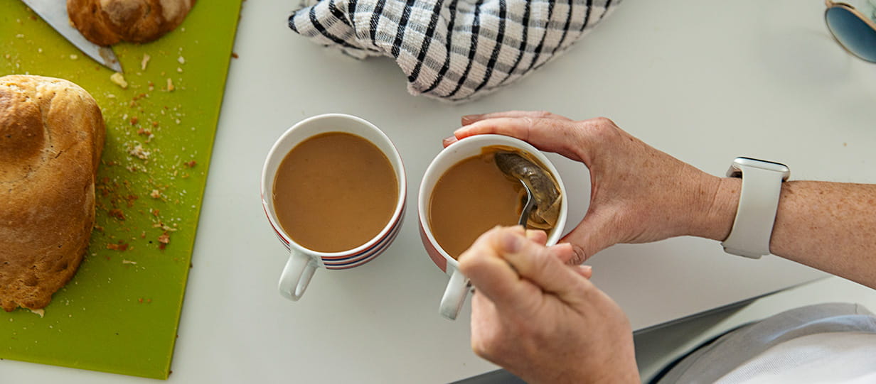 An older persons hands making a cup of tea