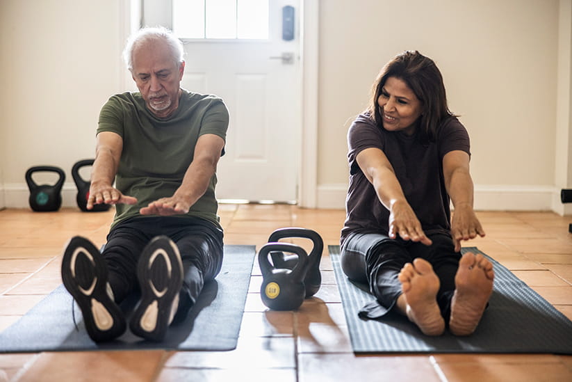 Senior couple stretching in home gym