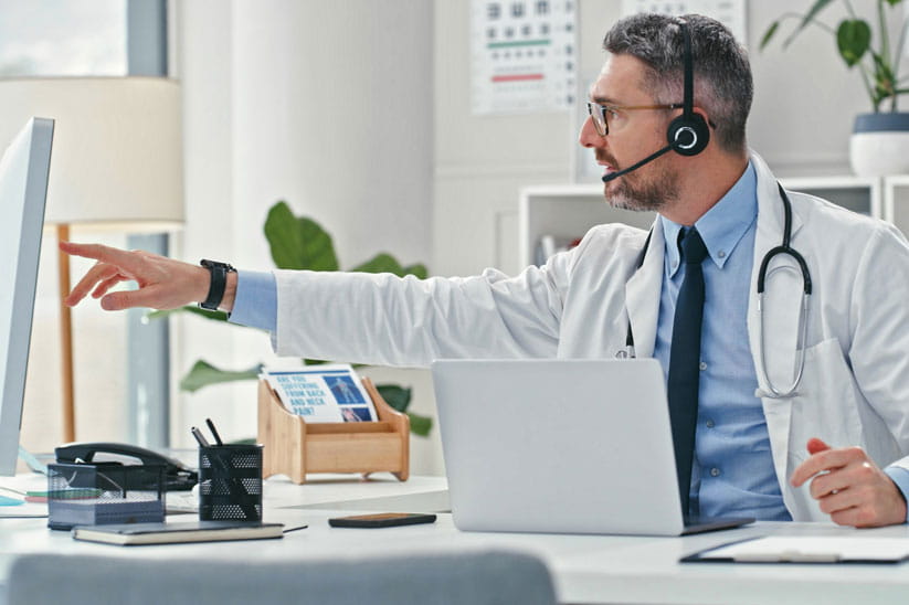 A specialist wearing a headset consulting online with a patient