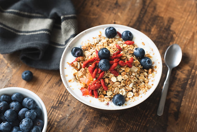 Granola bowl with yogurt, blueberries and goji berries on old wooden table. 