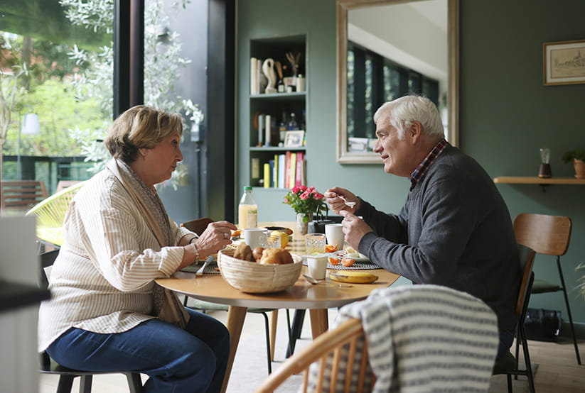 An older couple at a table eating breakfast