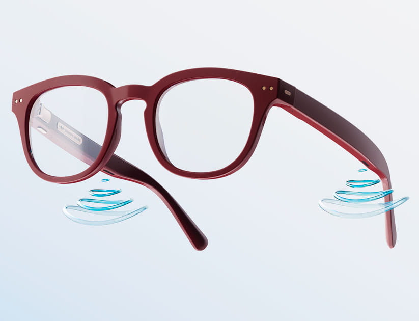 A pair of Nuance glasses with a dark red frame with stylised sound waves coming out of the rims