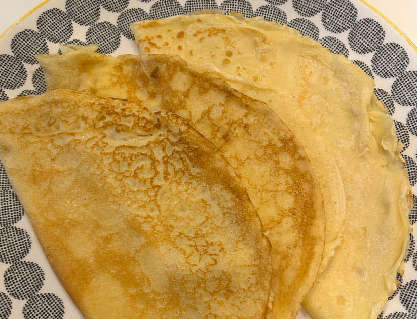 Three golden pancakes made using Mary Berry's recipe, folded in half on a patterned plate
