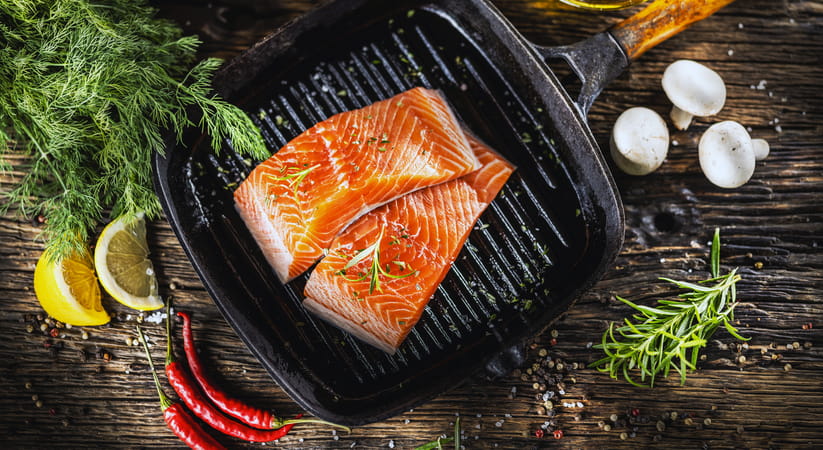 Two pieces of salmon cooking on a griddle pan