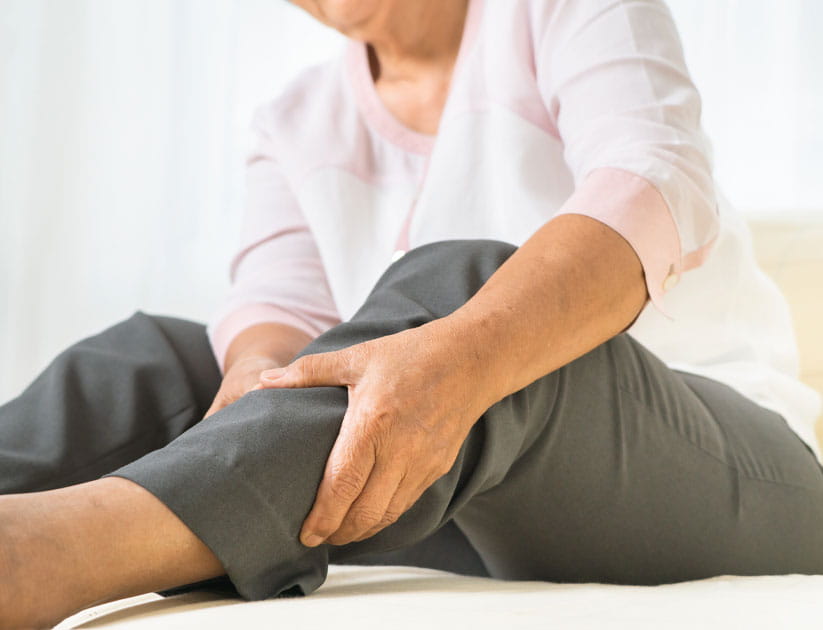 A mature woman holding her leg with a swollen ankle