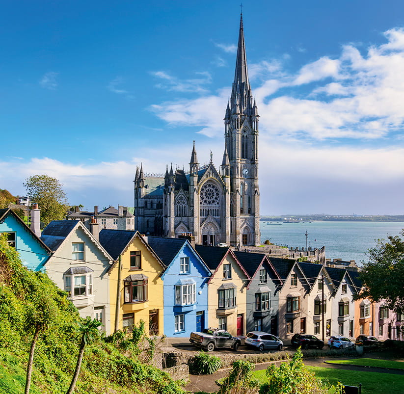 A picture of Cobh Cathedral with colourful houses in the foreground