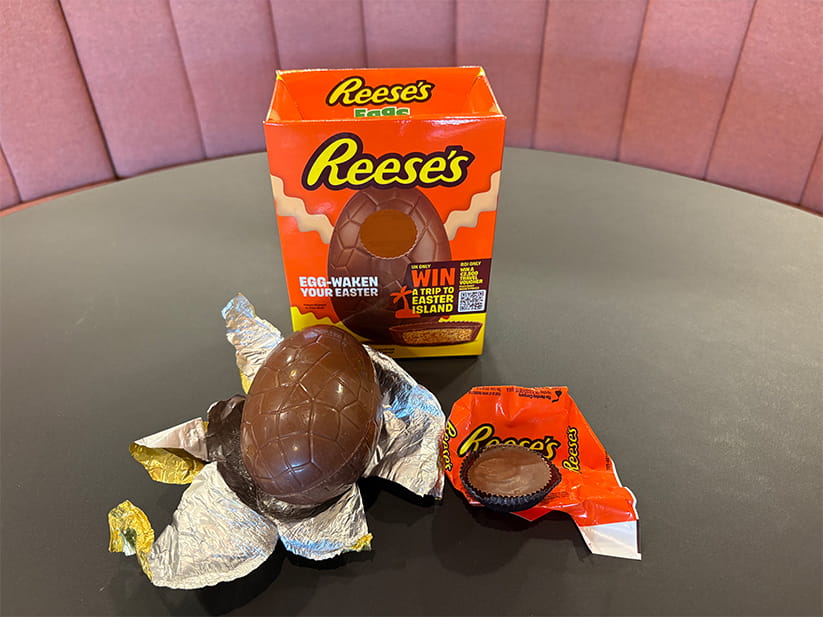 The Reese's Easter egg laid out on its foil, in front of the bright orange packaging box