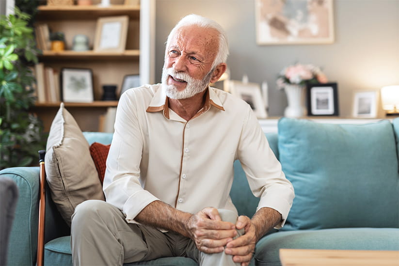 An older man holding his knee and looking pained