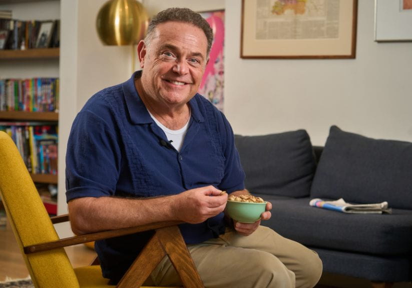 John Thomson sits looking at the camera with a bowl of pistachio nuts
