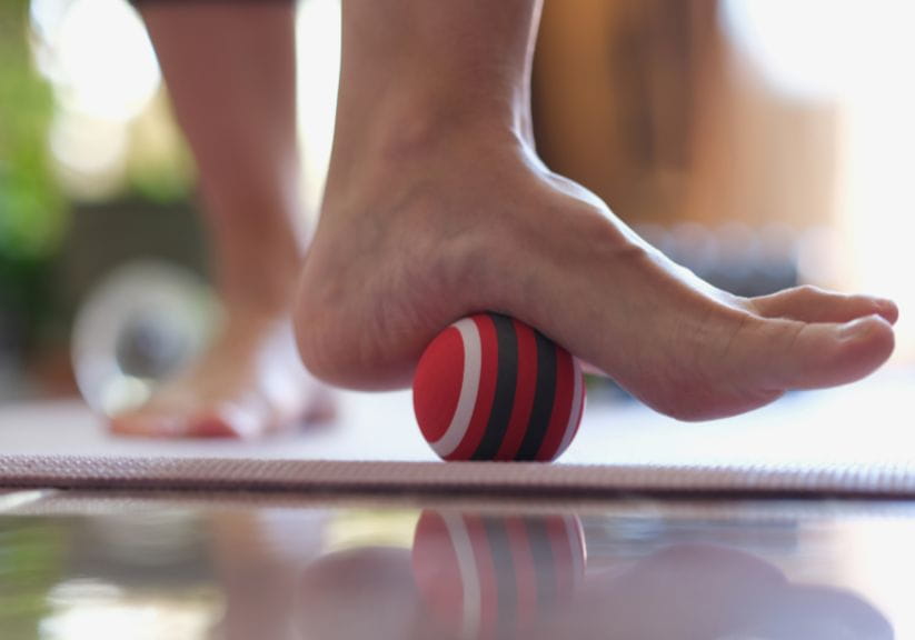 A person rolls their foot over a massage ball for physio