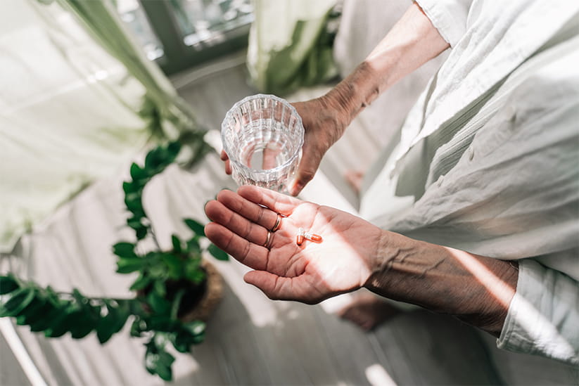 Pills or supplements in the palm of an elderly woman's hand close-up.