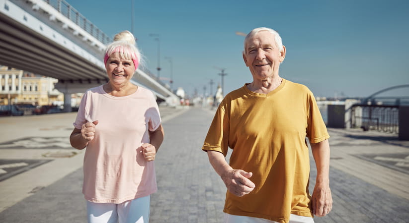 An older couple walking fast towards the camera on a beach promenade