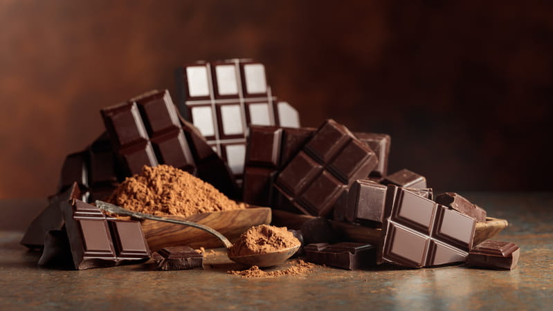 A heap of dark chocolate pieces against a brown background