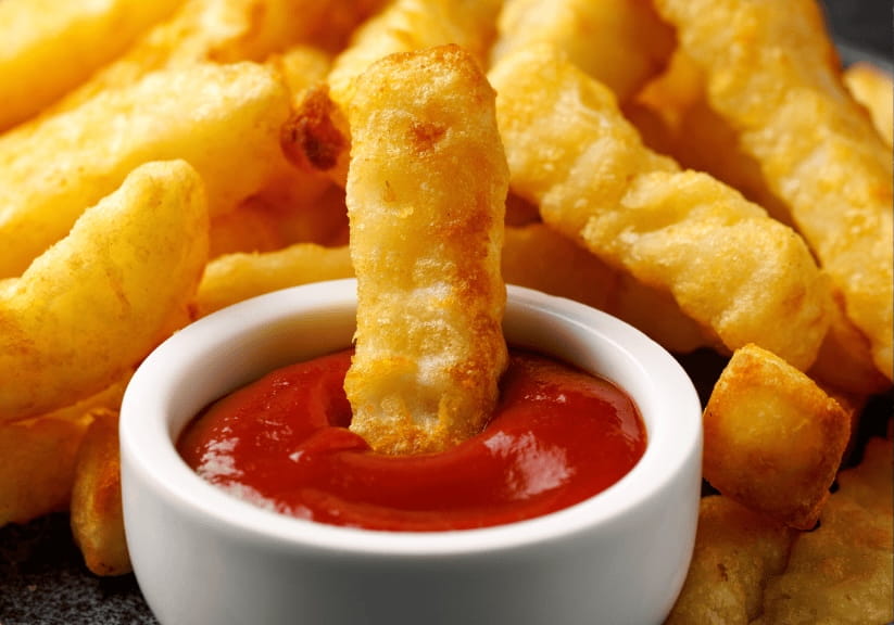 A chip being dunked in tomato ketchup